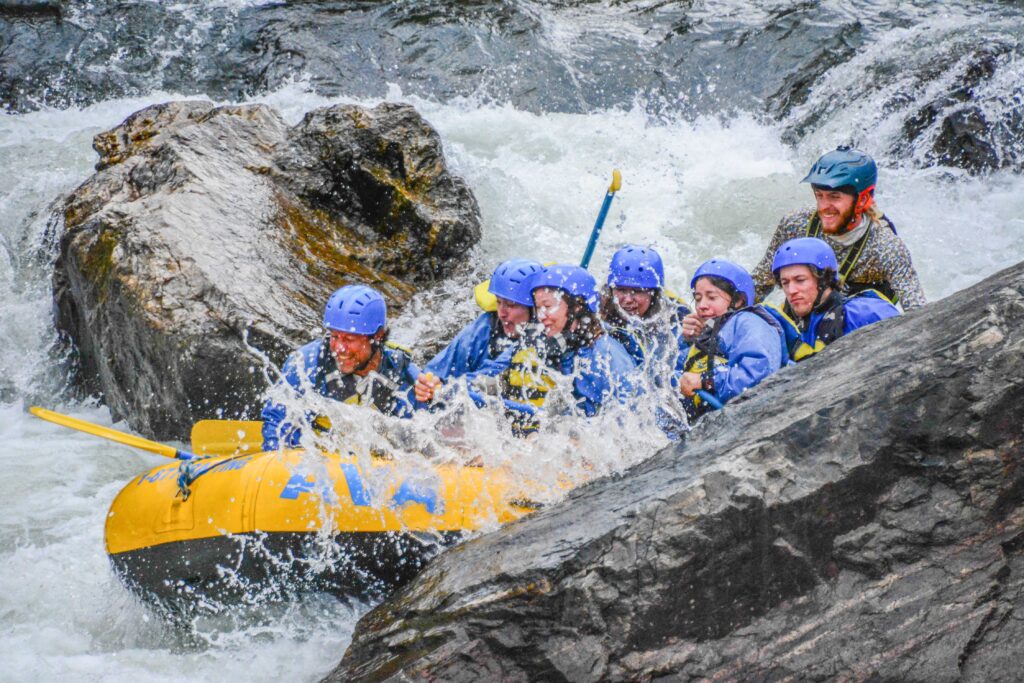 group rafting between rocks, as they hit the spray head on