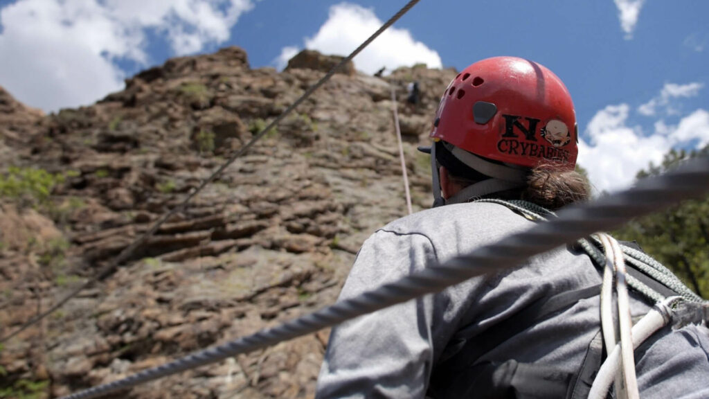 View from behind of a person belaying for rock climbers.